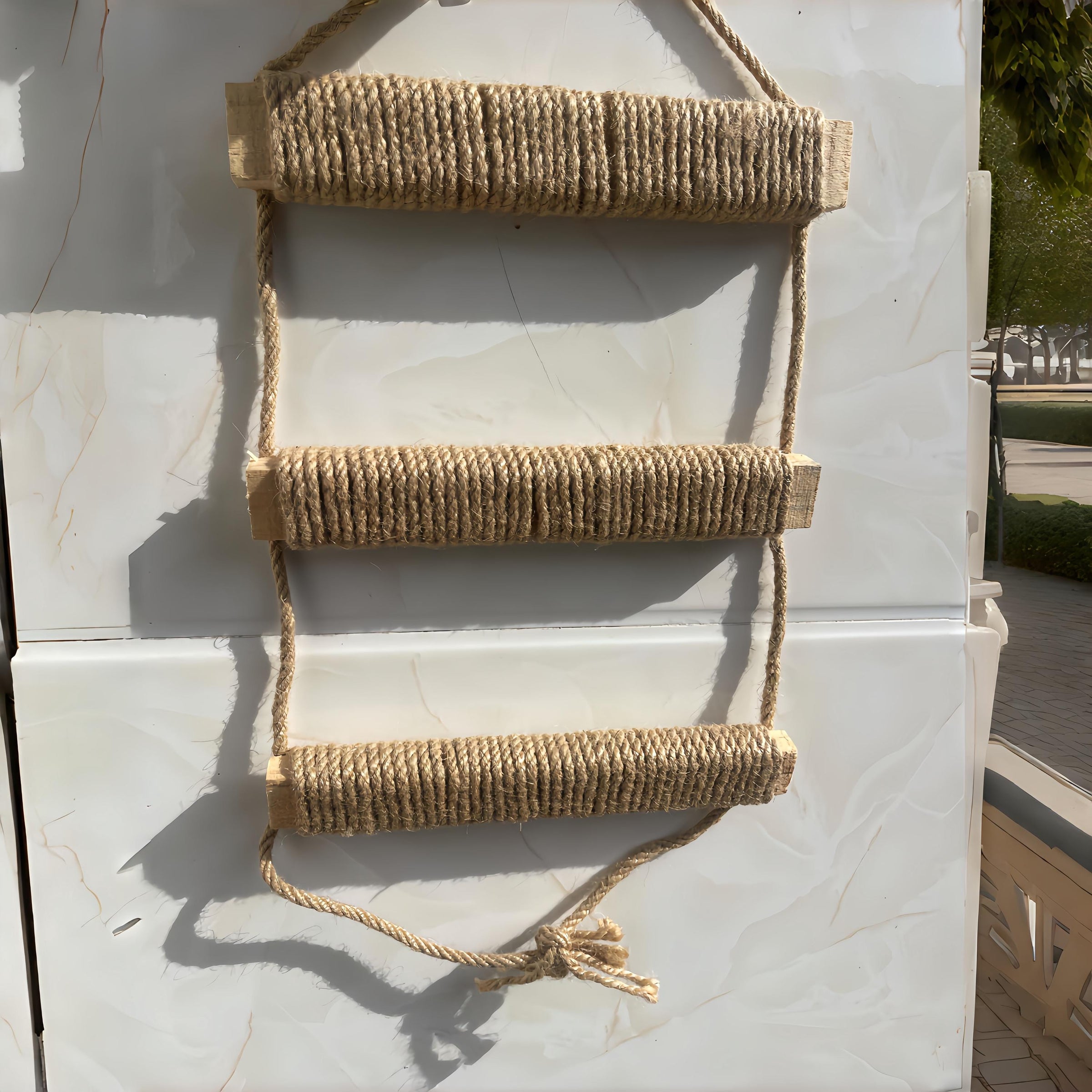 Three-rung cat climbing rope ladder showing the side ropes, wrapped wooden steps, and tied lower end